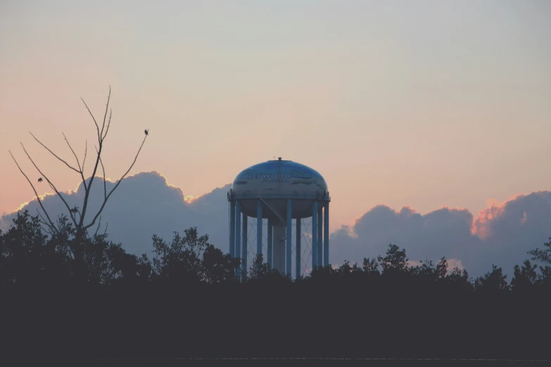 the water tower is silhouetted against a colorful sunset