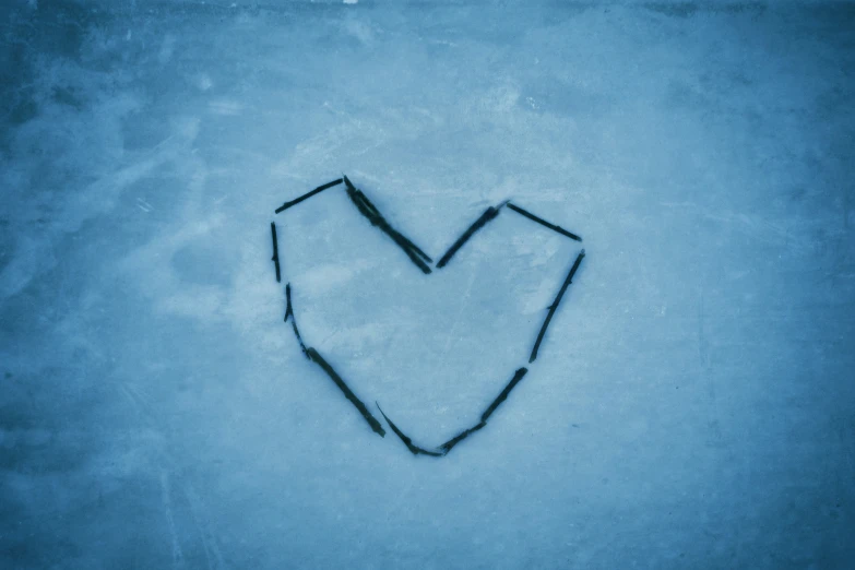 a heart - shaped object drawn on ice with a small amount of black ink