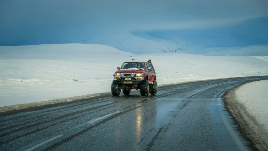 a jeep driving down a snow covered road