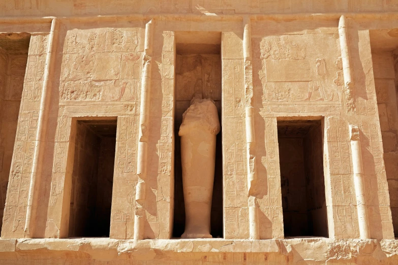 an old stone building with two statues in it