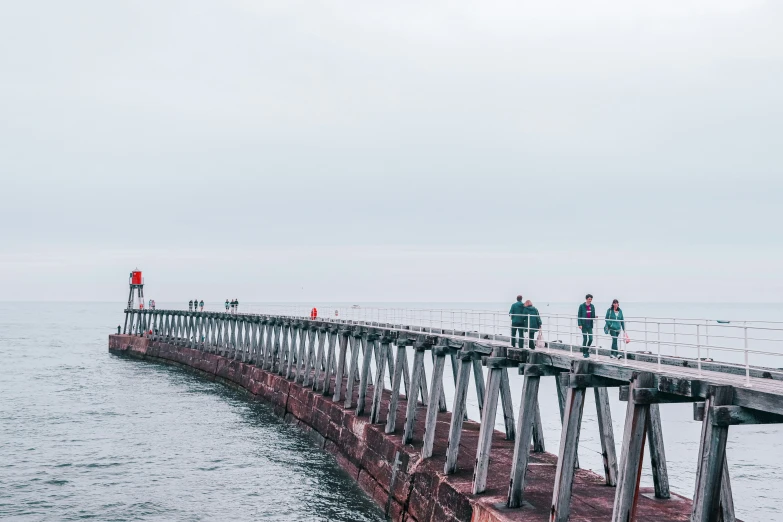 people walk on the edge of the pier while others are on a boat