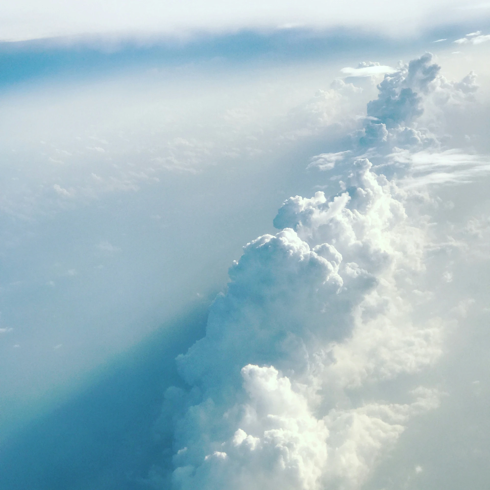 an airplane wing flying under clouds and the ground