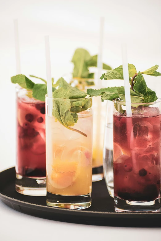 four different drinks with straws and garnishes are in cups