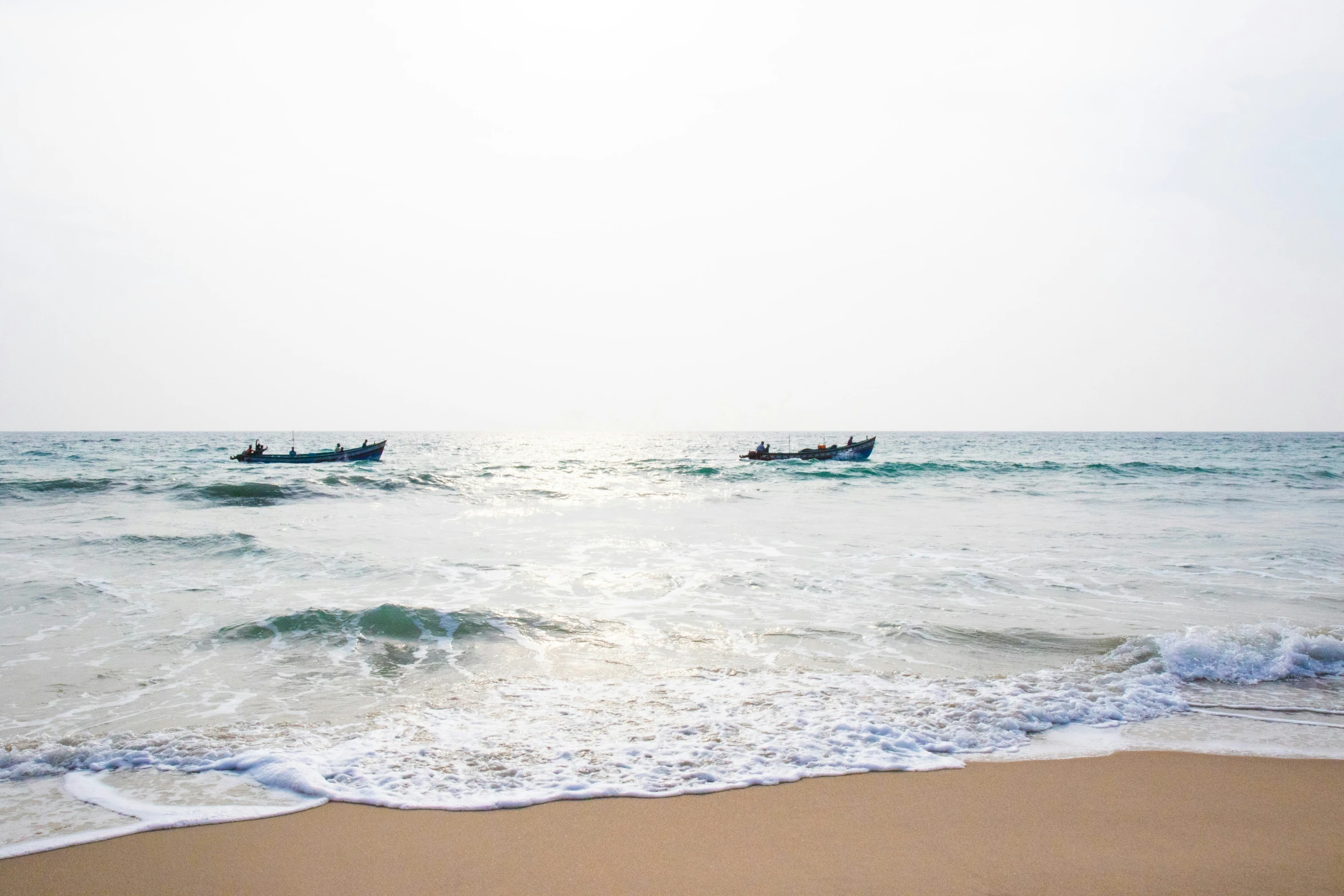 two boats on the water and a beach with waves