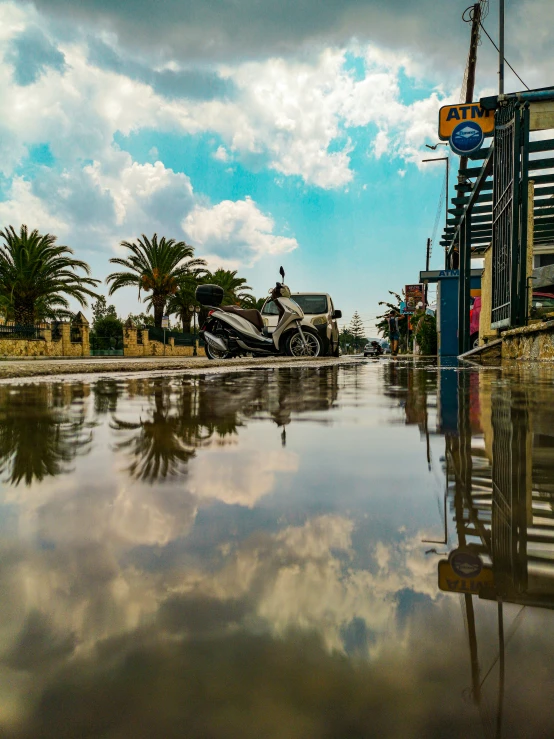 a building is reflected in the water with palm trees