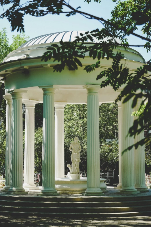 a gazebo with statues inside sitting among trees