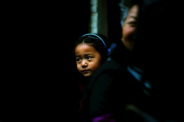 a woman standing next to a child on a black background