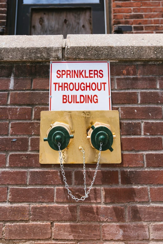 an emergency sign that has two lights attached to the brick wall