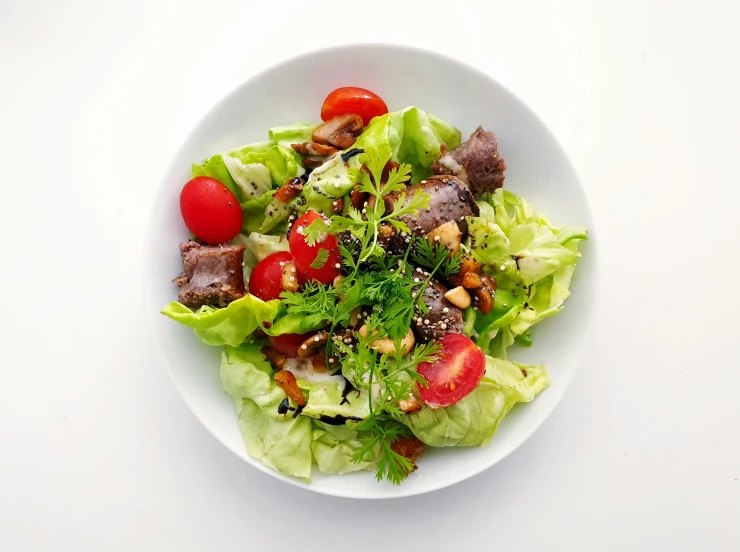 salad served on a white plate, with tomatoes