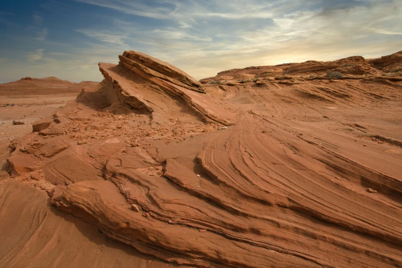 a rocky, stretch of land covered in sand under a blue sky