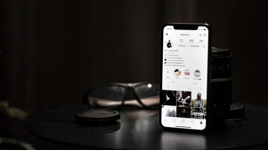 an iphone next to a pair of glasses and a tinsel on a table