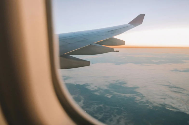 the view from inside an airplane shows the wing over water and clouds