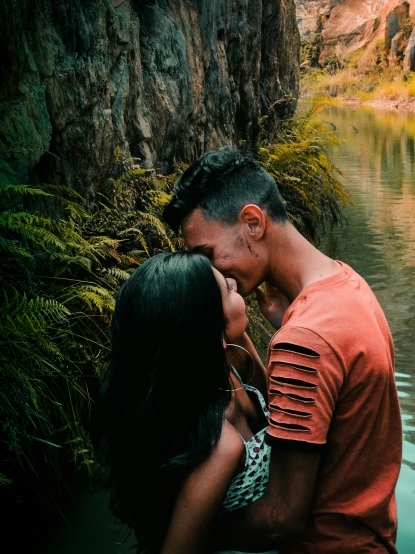a man and woman who are kissing near the water