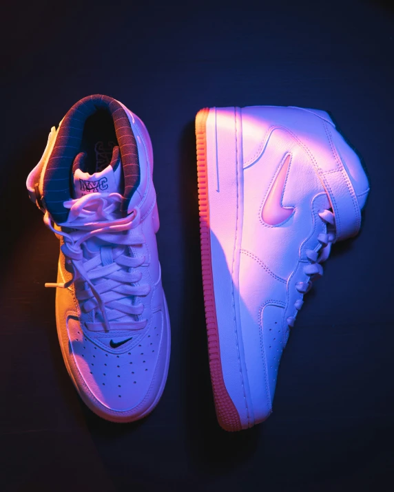 a couple of white sneakers sitting on top of a wooden floor