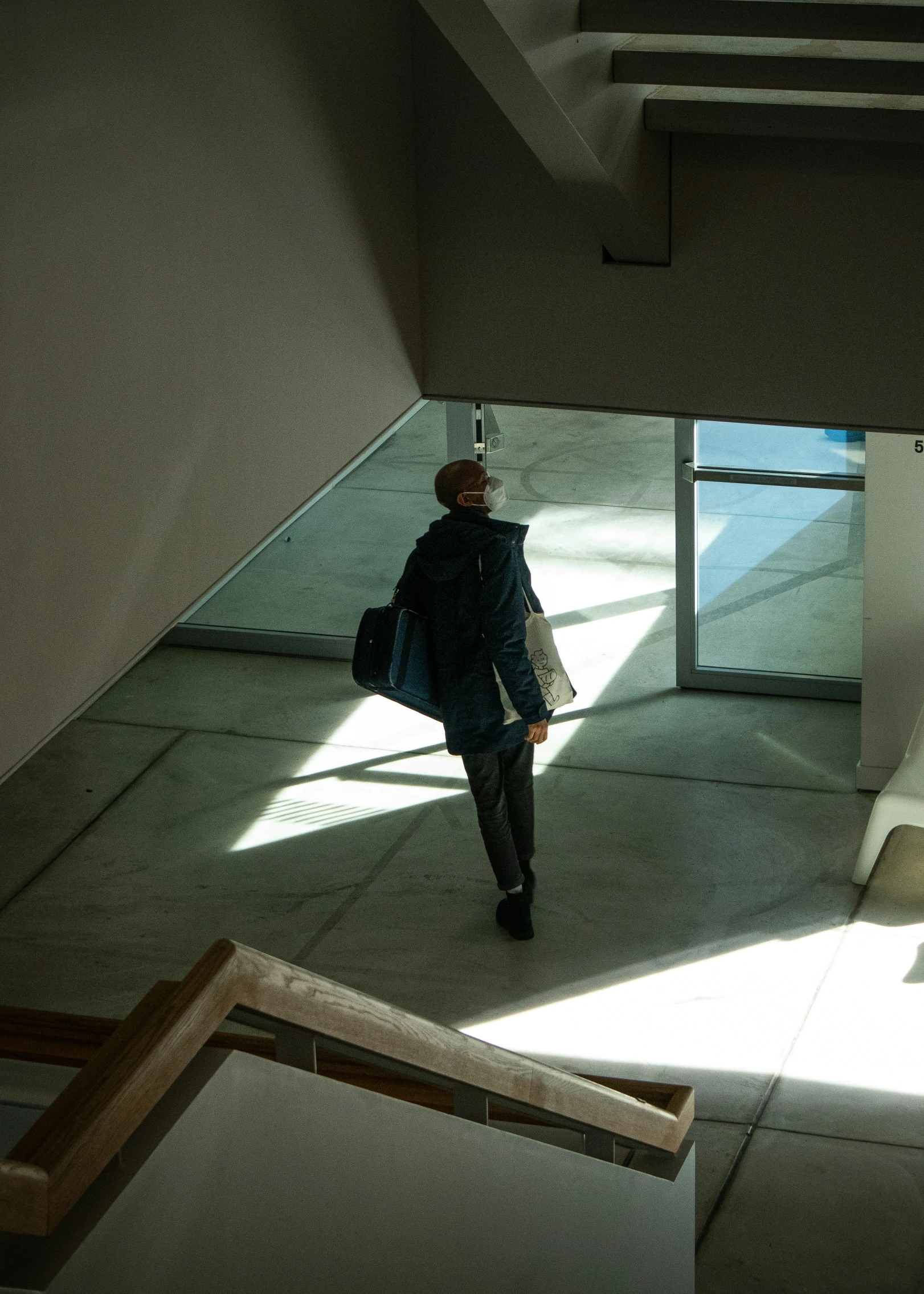 a man in black clothes and coat walking towards a building