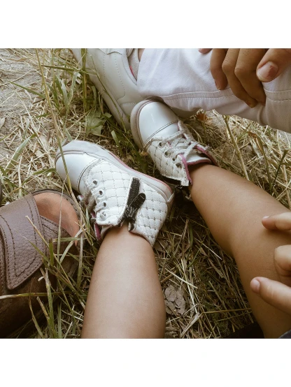 two people sitting in the grass with their hands on their feet