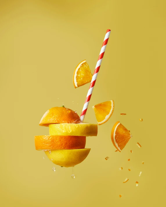 orange slices are falling into a bowl with a straw