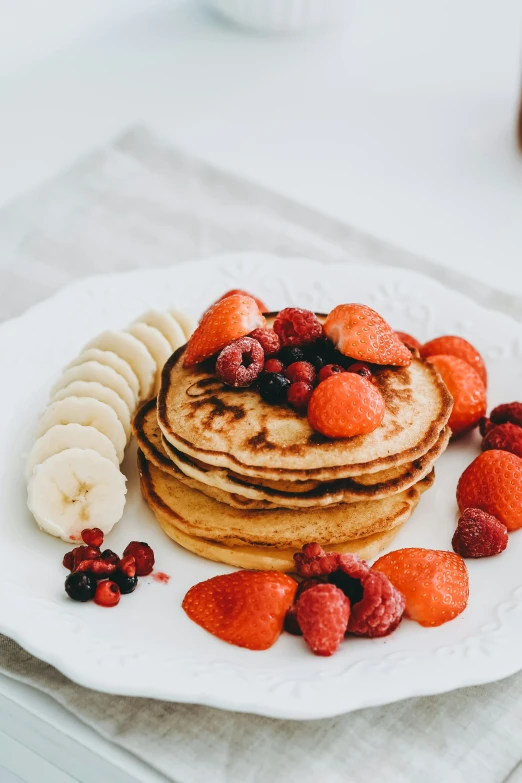 fruit is sitting atop a stack of pancakes on a plate