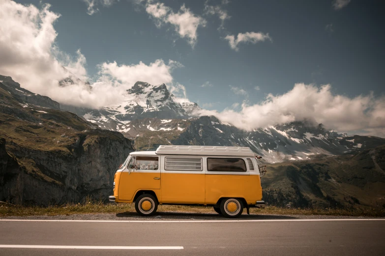 a yellow and white camper van on the side of a mountain road