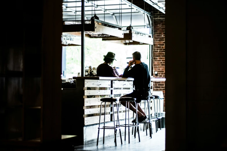 two people sit at a table, one with a hat on