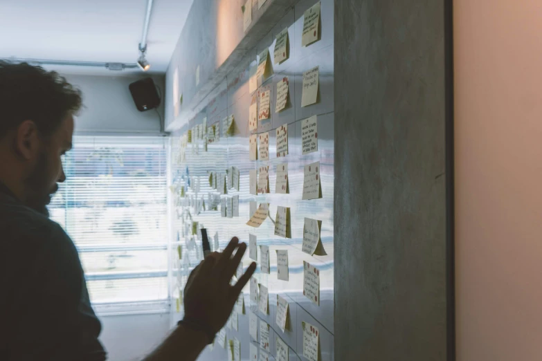 man writing on a white board with notes on it