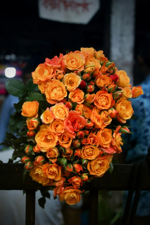 a large orange flower bunch sits on a railing