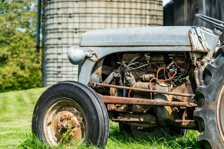 an old tractor is pictured in the foreground and is next to a silo