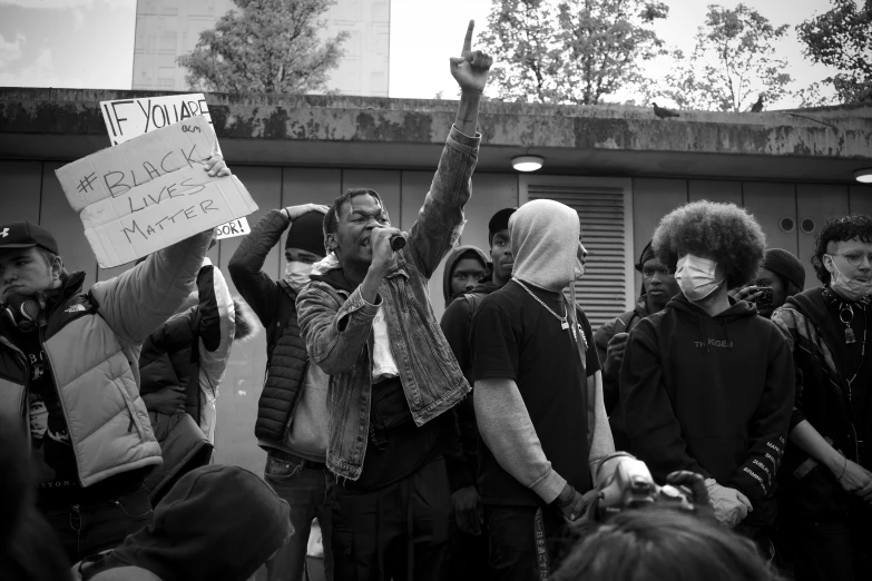 a group of people standing outside with one holding a sign and a helmet