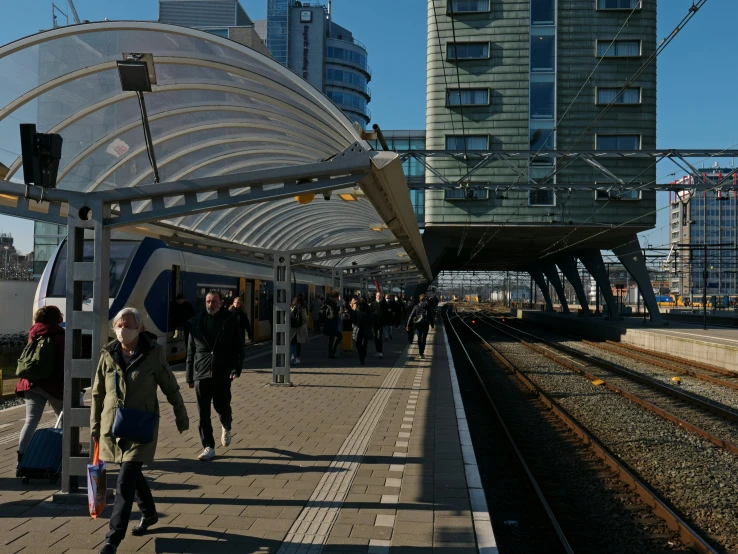 passengers wait at a train station on the rails