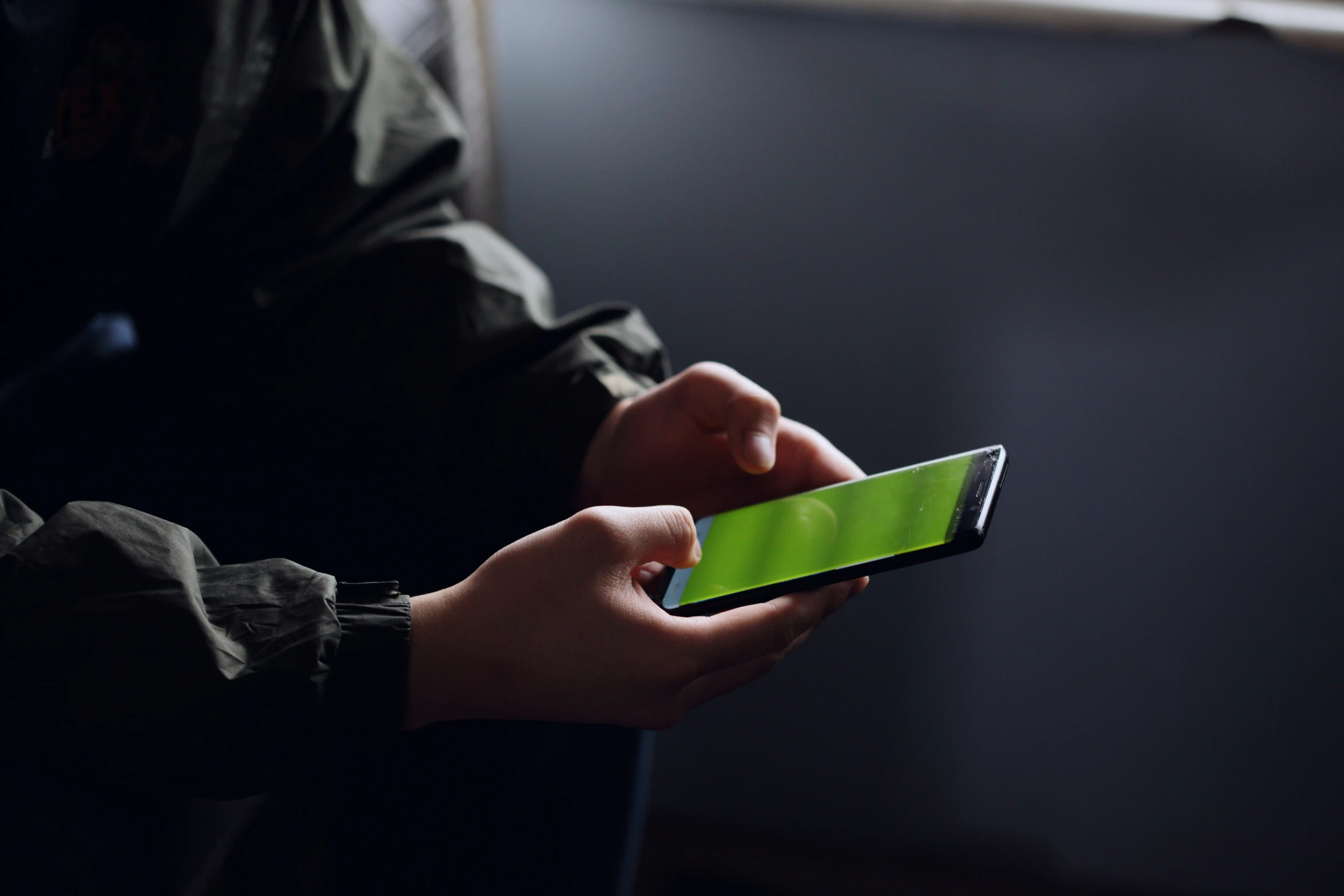 someone is using a green cellphone in the dark