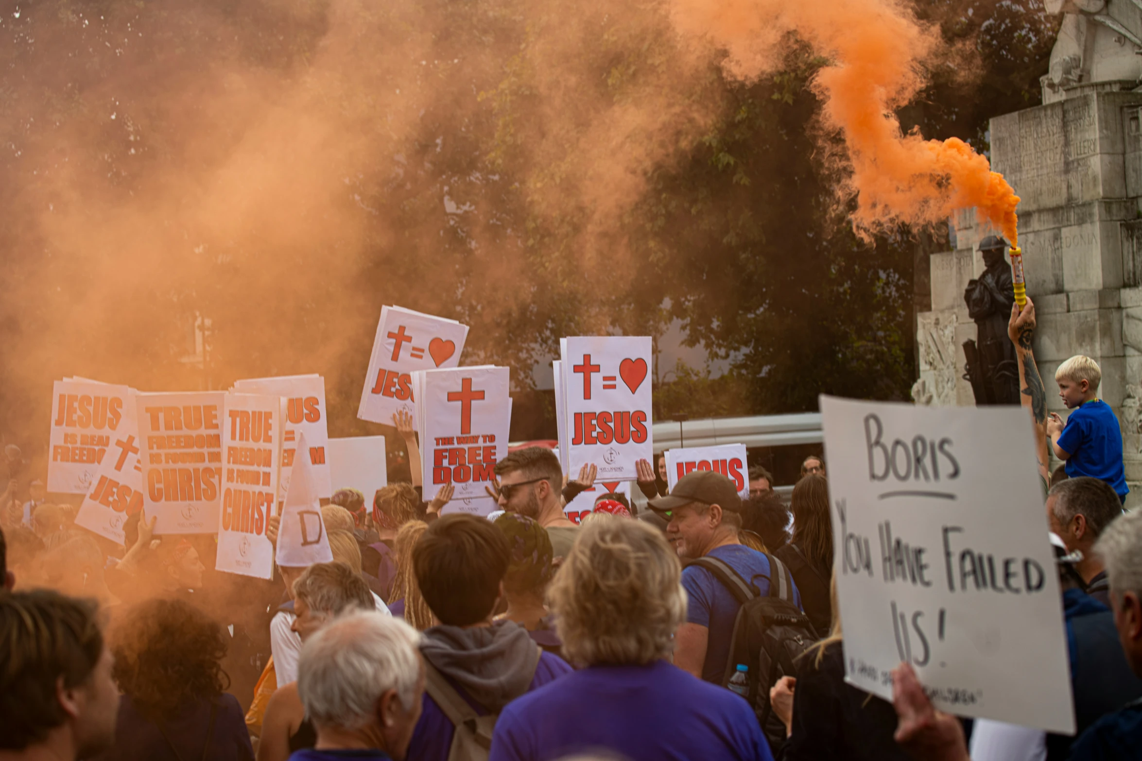 a crowd of people holding signs next to a sky of smoke