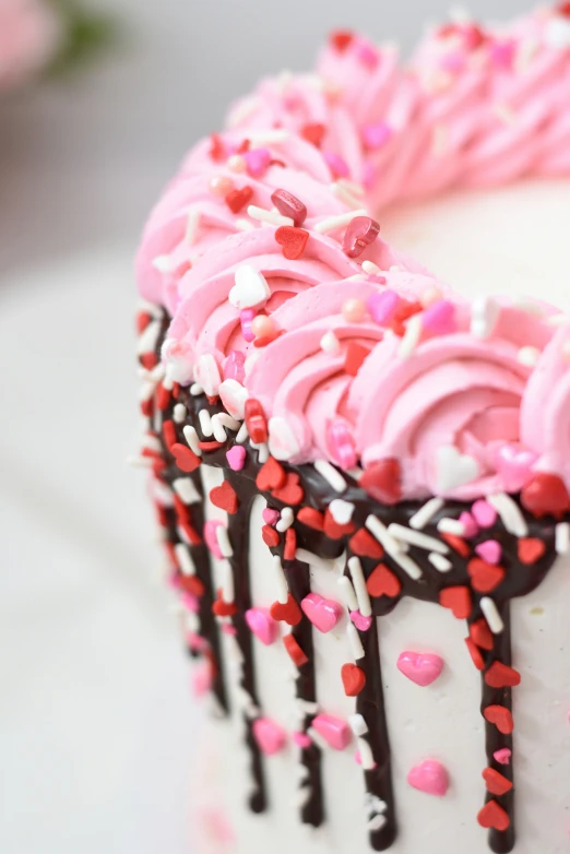 white and pink frosted cake with red hearts and sprinkles