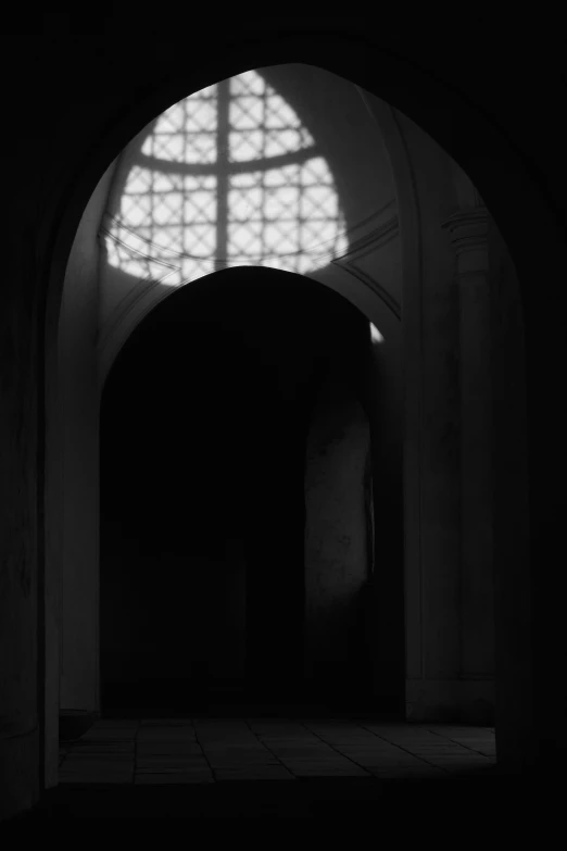 a light coming through a small archway into another room