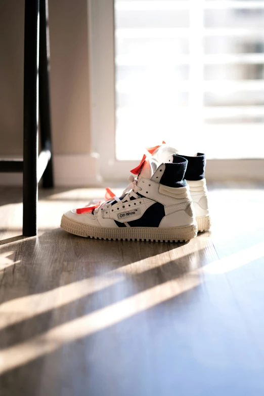 a pair of sneakers on a wooden floor in front of a window