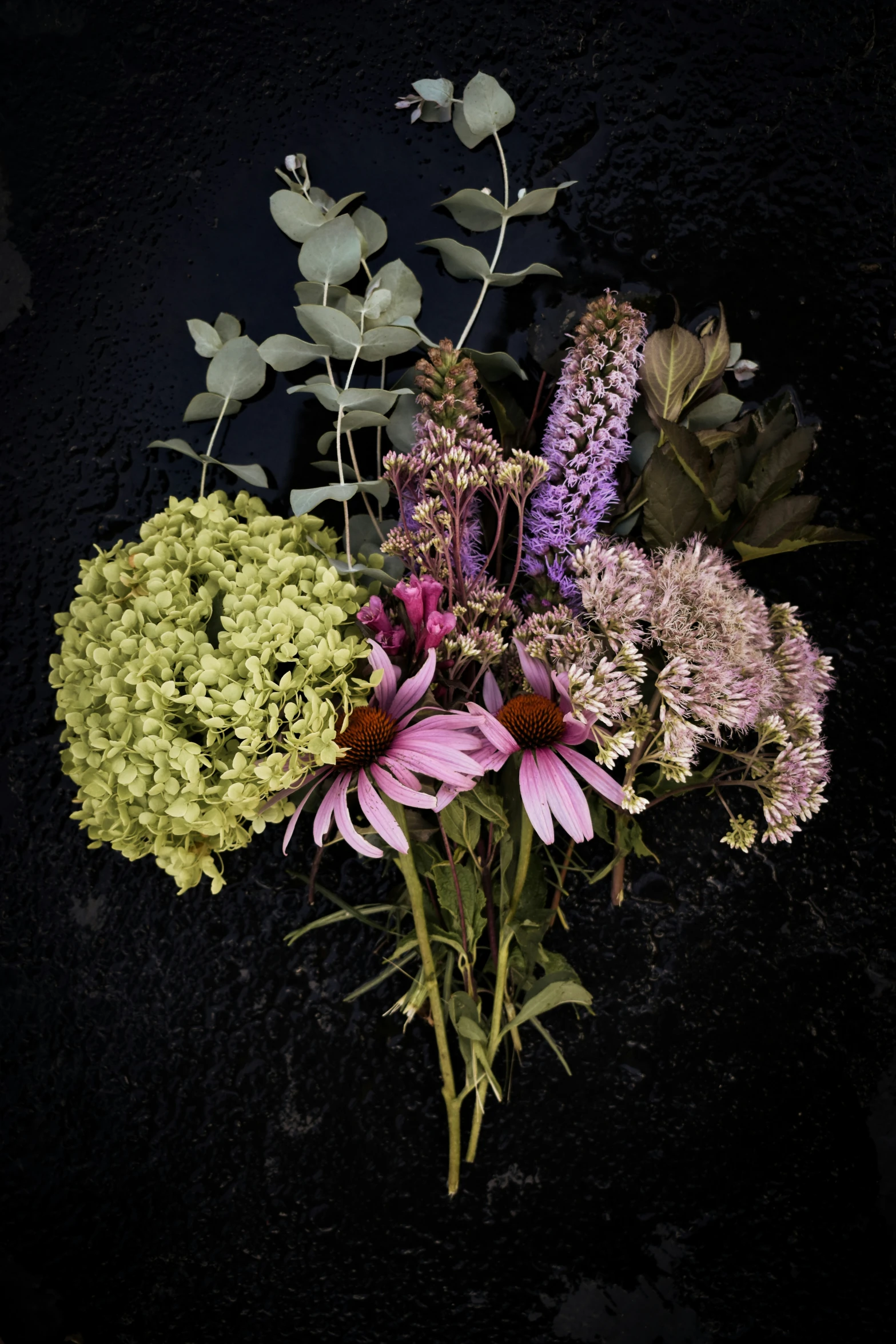 a flower bouquet of different colors sits against a black background