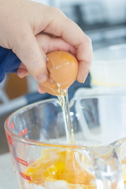 someone adding an egg to the top of a mixer