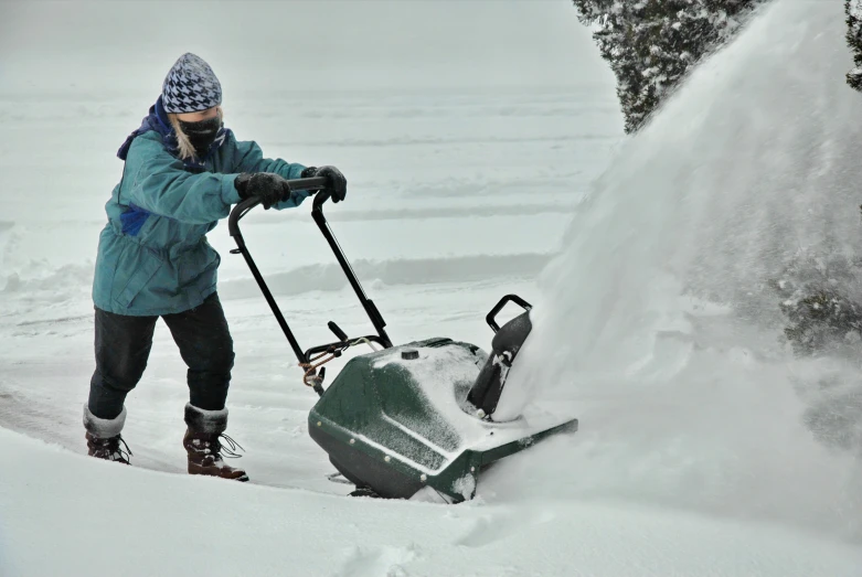 man shoveling snow on a driveway with a sleigh