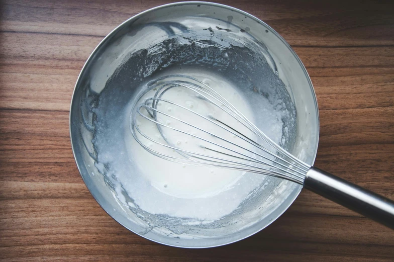 whisk in a bowl on a wood surface