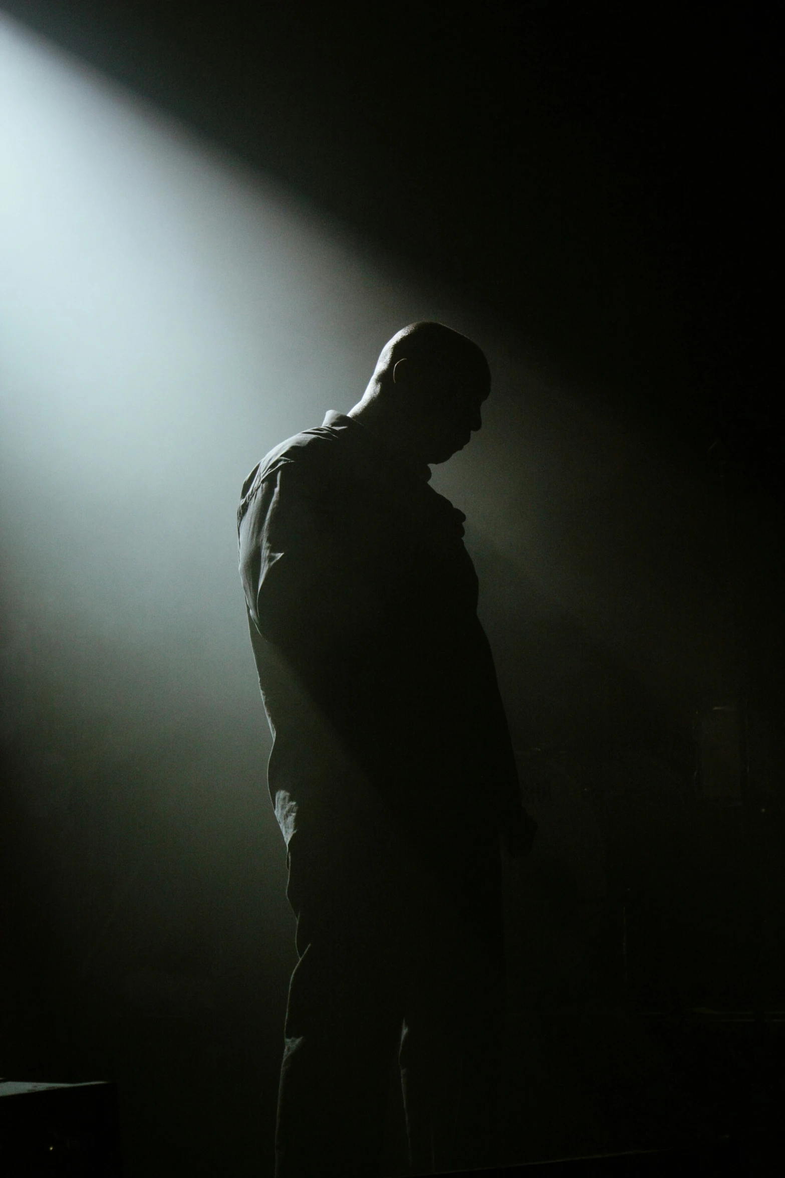 a person in a hooded jacket standing under a spotlight