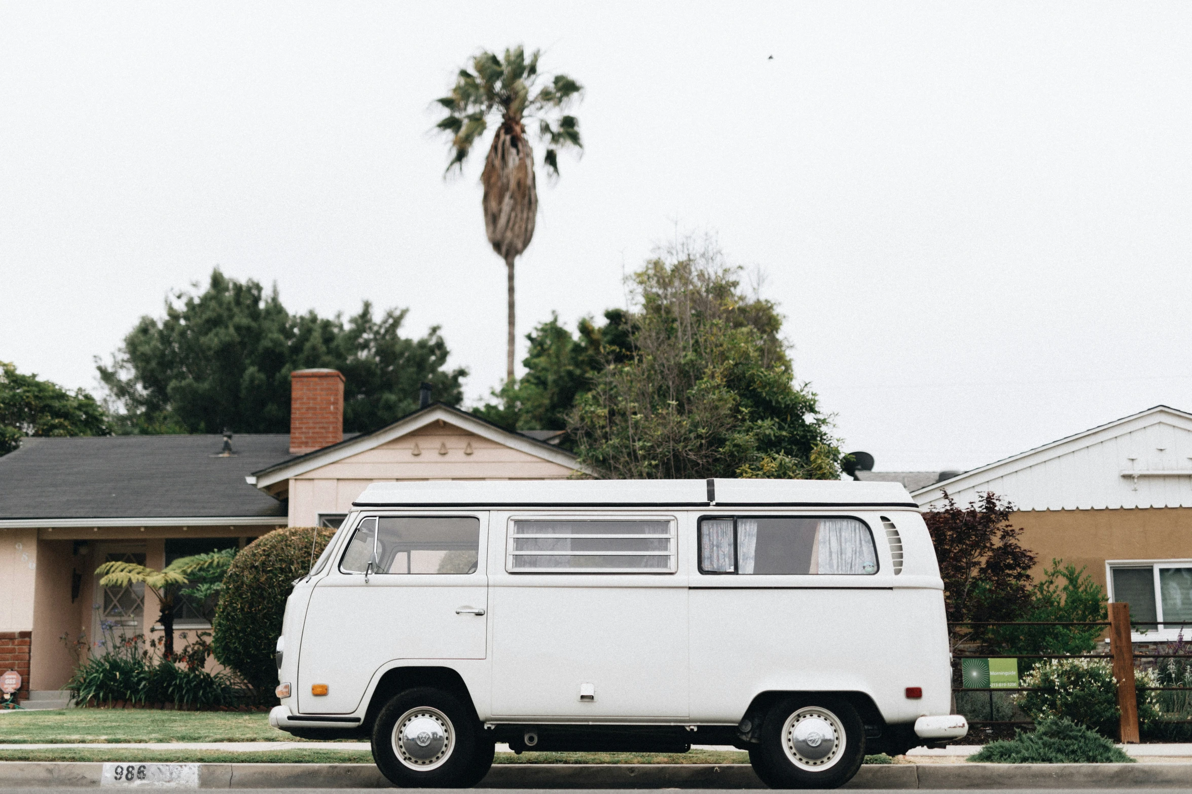 a vintage vw bus is parked on a sidewalk in front of a house