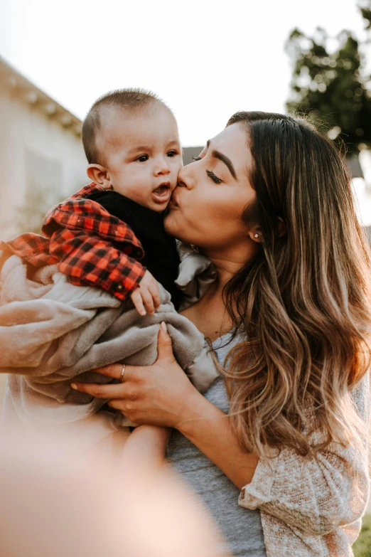 a woman kissing her baby boy on the nose