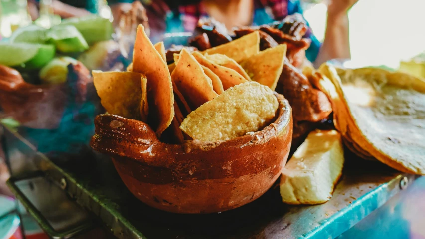 a large serving tray holding many tortilla chips and  dogs