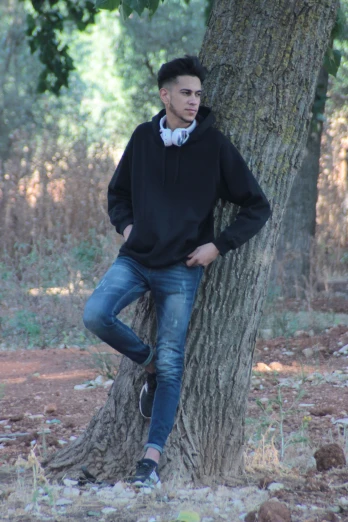 a young man in a hoodie sitting on a tree