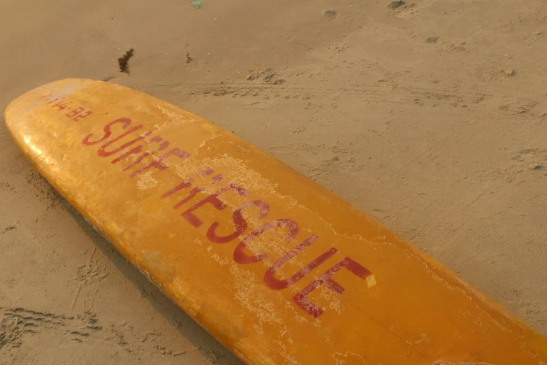 an orange surfboard laying on its side at the beach
