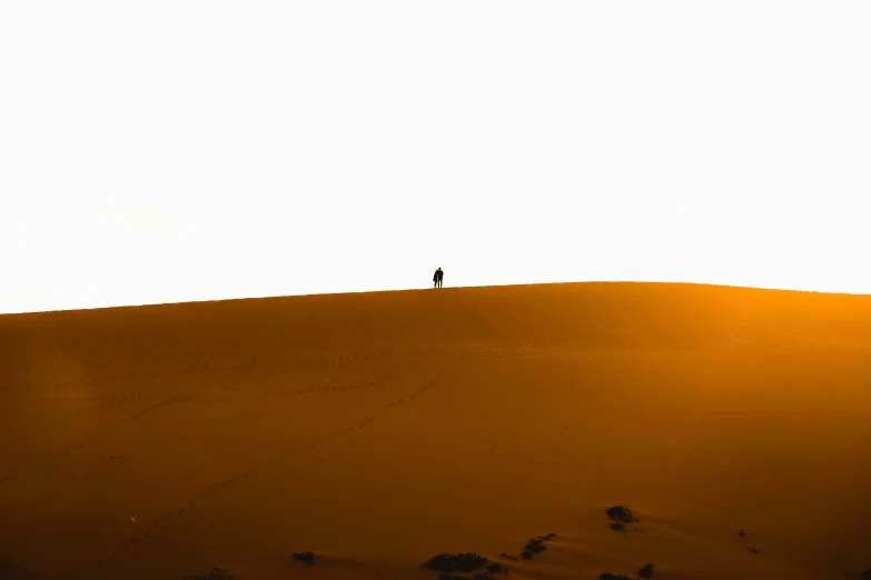 two people stand in the desert at sunset