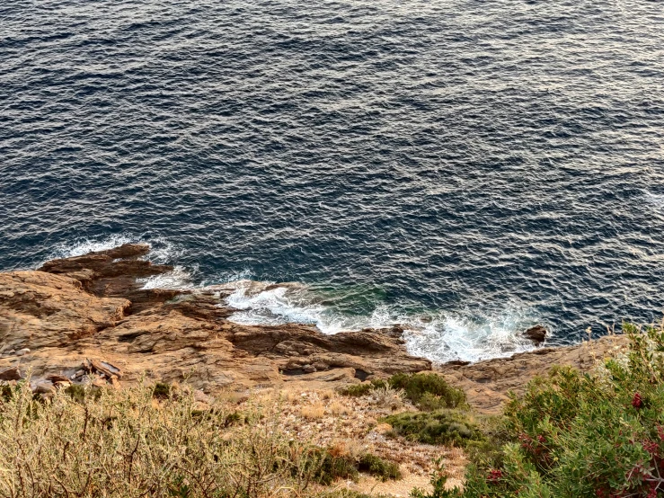 two people on a cliff facing the water