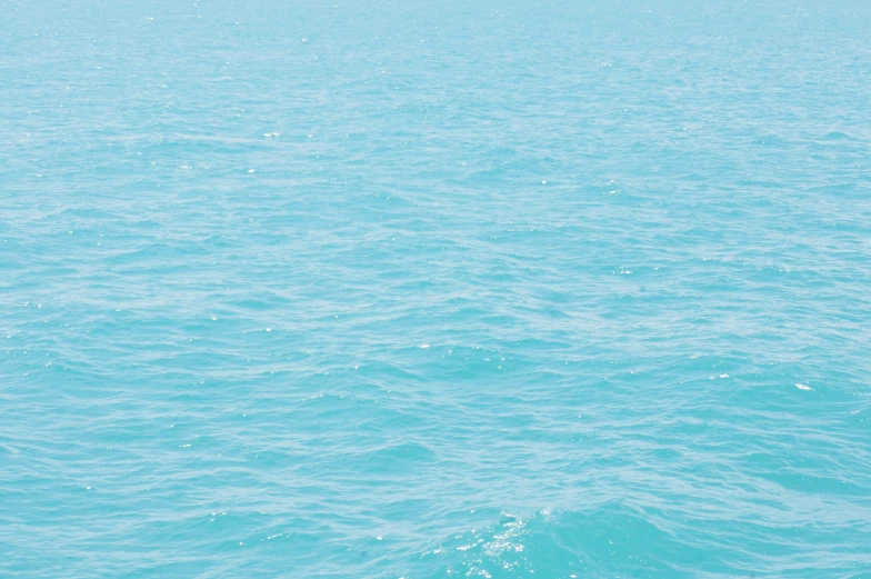 an airplane is flying over the ocean in blue