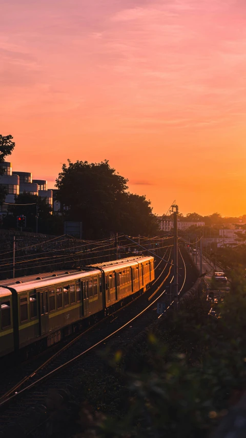 the sun sets over a railroad track with a train on it