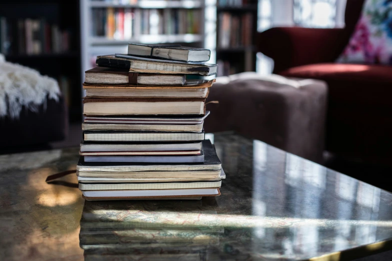 several books are piled on top of each other in a room