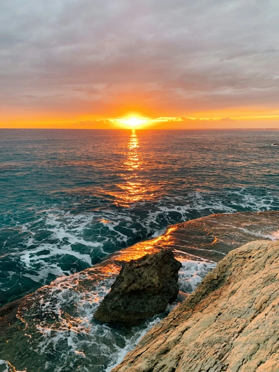 a sunset over the ocean on top of a cliff